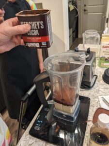 Hershey's cocoa powder near a blender of ice cream ingredients
